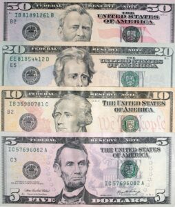 Four different dollar bills placed on a flat surface.