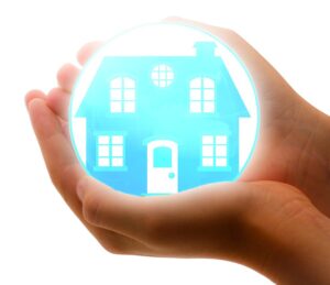 Two hands put together, holding a blue house, which seems to in in some kind of a ball that is illuminated. The picture gives a sense of a house which is being protected, and there is nothing better for that than moving insurance. 
