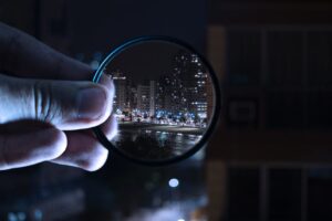 The photo of a person holding a magnifying glass through which a part of the city at night can be seen. Glass is a breakable material, and it is difficult to safely pack valuable and fragile items. 