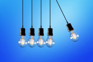 Five light bulbs hanging from the ceiling in front of a blue background.