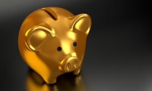 Our prices won`t break the bank. A gold piggy bank on a black surface.
