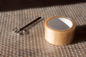 Pair of scissors and roll of duck tape on bubble wrap.
