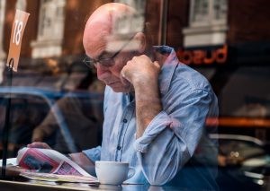 Older gentleman reading the paper in a coffee shop.