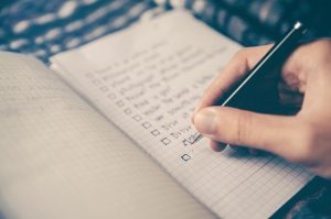 Write down everything you need to take care of after the move A person writing the tips for settling in Saddle River NJ