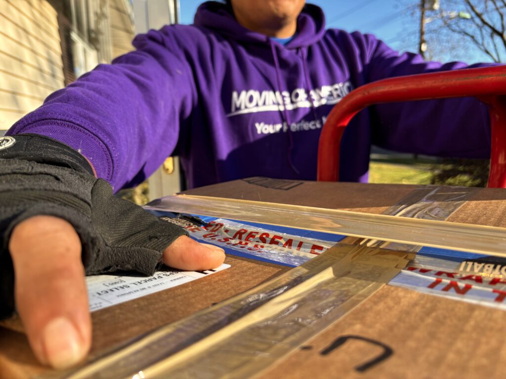 Moving of America appliance movers lifting and transporting a heavy refrigerator in New Jersey.
